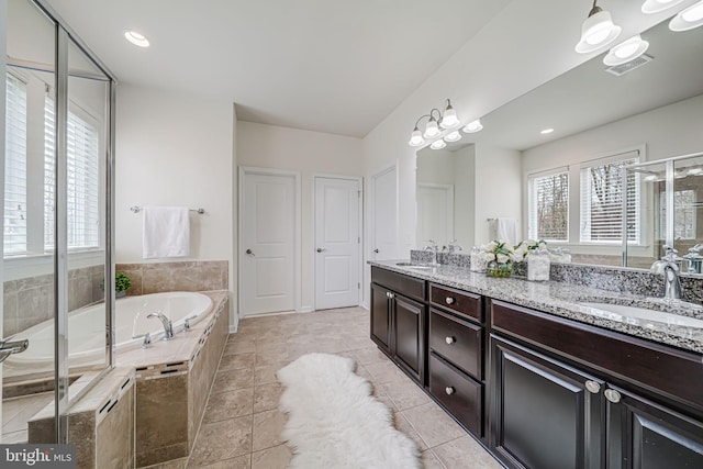 full bath with plenty of natural light, a bath, double vanity, and a stall shower
