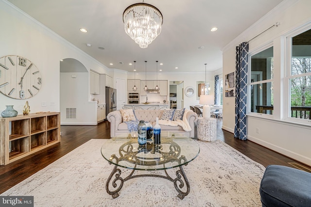 living area with dark wood-style flooring, arched walkways, ornamental molding, baseboards, and recessed lighting