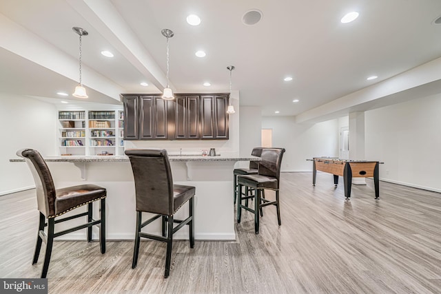 bar area featuring light wood finished floors, recessed lighting, pendant lighting, and baseboards