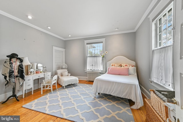 bedroom with radiator, baseboards, ornamental molding, and wood finished floors