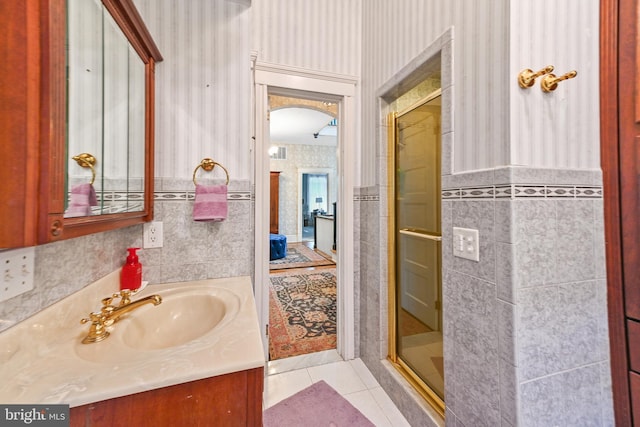 full bath featuring vanity, tile walls, wallpapered walls, tile patterned floors, and a stall shower