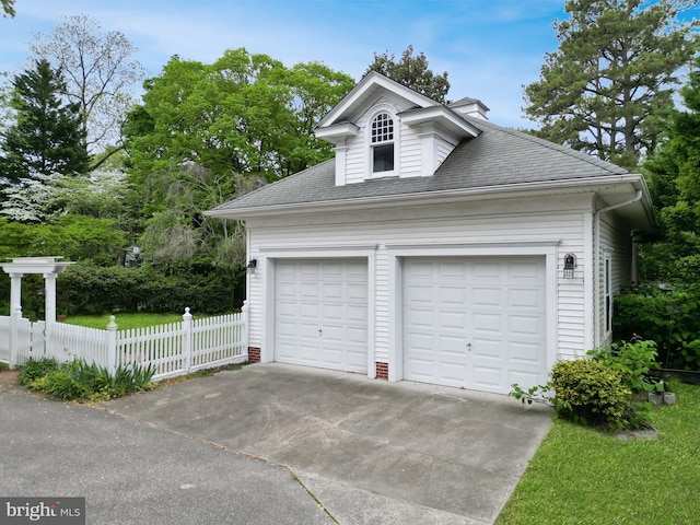 garage with fence and concrete driveway