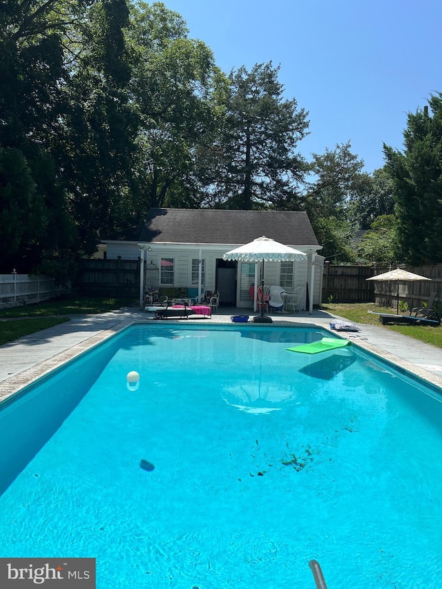 view of pool with a fenced in pool, a fenced backyard, a patio area, and an outbuilding