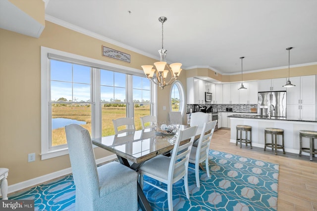dining room with a chandelier, ornamental molding, and light wood finished floors