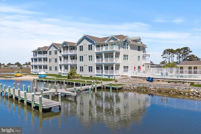 dock area with a community pool, fence, and a water view