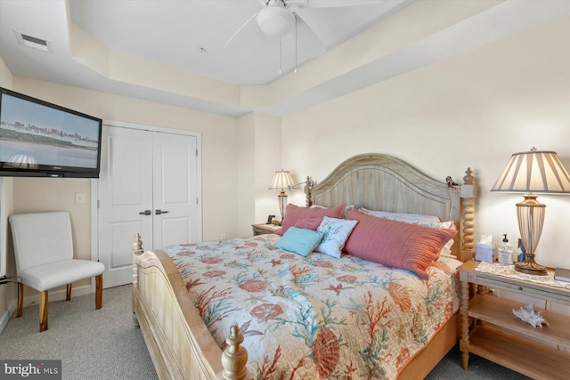 bedroom with carpet flooring, a raised ceiling, a ceiling fan, visible vents, and a closet