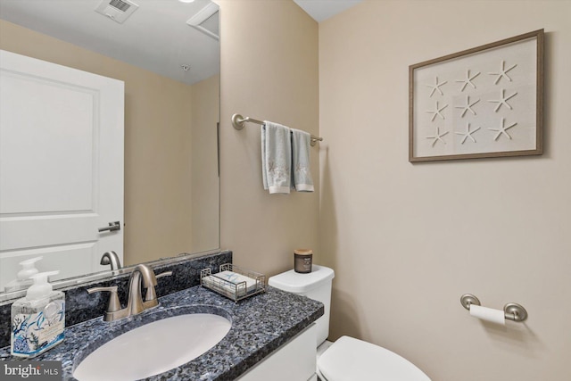 half bath with visible vents, toilet, and vanity