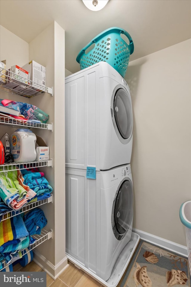 laundry room featuring laundry area, stacked washer / drying machine, and baseboards