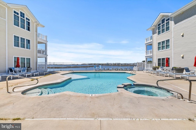 view of pool with a patio area, fence, and a pool with connected hot tub