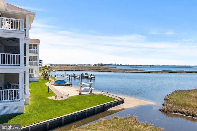 view of dock with a lawn and a water view