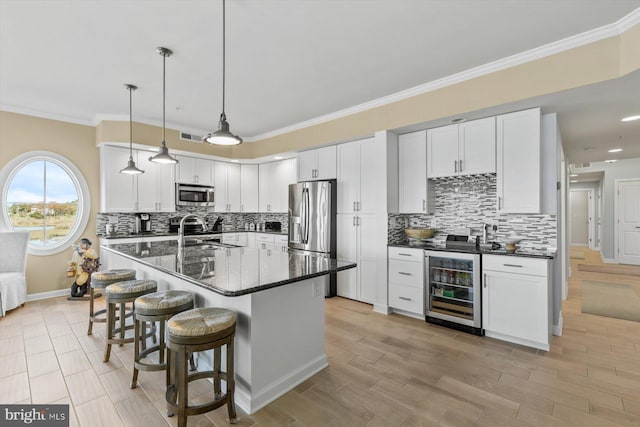 kitchen with appliances with stainless steel finishes, a kitchen breakfast bar, tasteful backsplash, wine cooler, and ornamental molding
