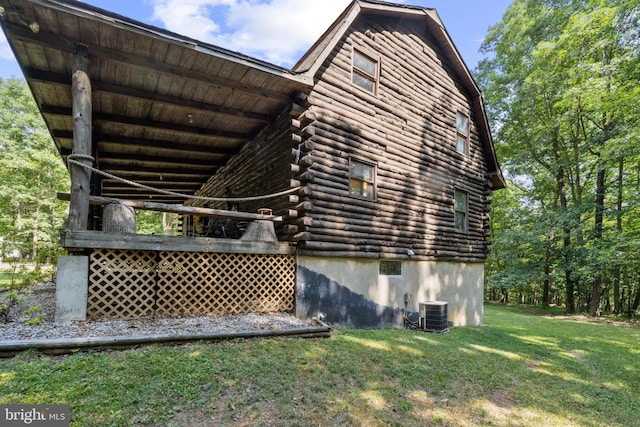 view of home's exterior featuring a lawn, log exterior, and central AC unit