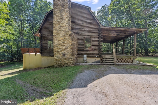 view of side of property featuring a lawn, a chimney, and log siding