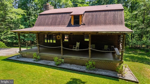 rear view of house with a shingled roof, a wooden deck, a yard, and log exterior