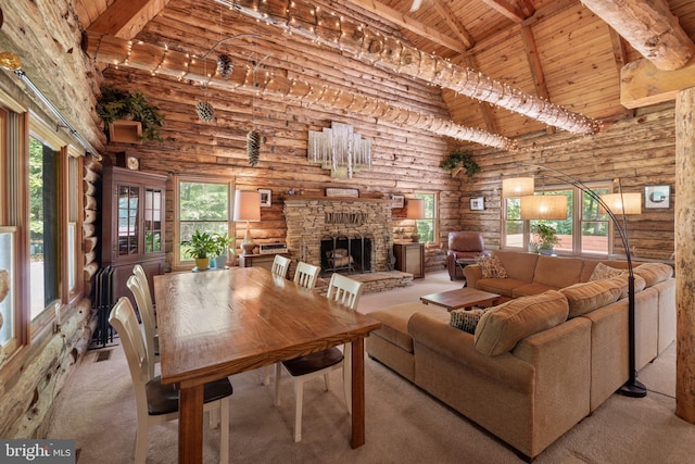 carpeted living area featuring a towering ceiling, rustic walls, beamed ceiling, a stone fireplace, and wooden ceiling
