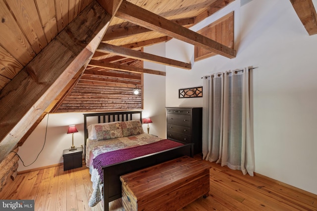 bedroom with vaulted ceiling with beams and hardwood / wood-style floors