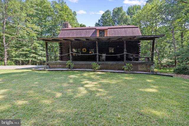 log-style house featuring a porch, log exterior, a chimney, and a front lawn