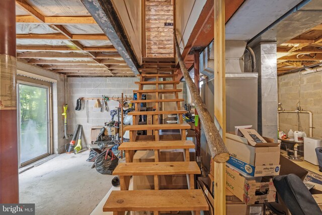 stairway featuring concrete block wall and unfinished concrete floors