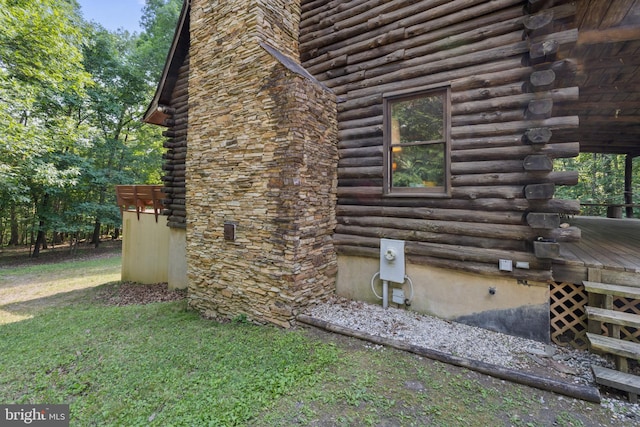 view of home's exterior featuring a lawn, a wooden deck, and log siding