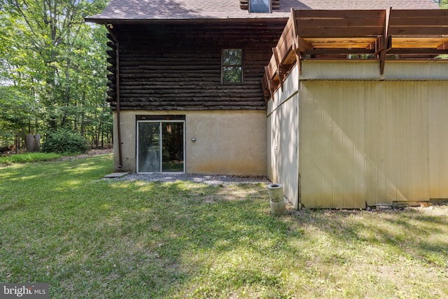 rear view of property featuring roof with shingles, log exterior, and a yard