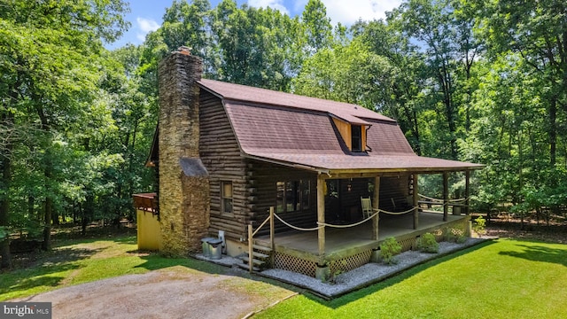 exterior space featuring a front lawn, a gambrel roof, roof with shingles, a chimney, and log exterior