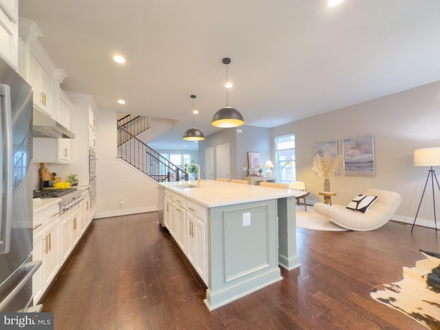 kitchen with light countertops, a sink, a kitchen island with sink, and white cabinetry