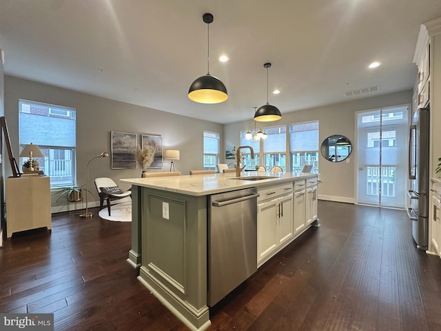 kitchen with visible vents, appliances with stainless steel finishes, a center island with sink, a sink, and white cabinets