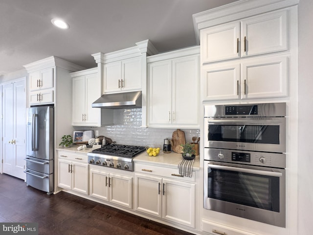 kitchen with light countertops, dark wood finished floors, appliances with stainless steel finishes, and under cabinet range hood