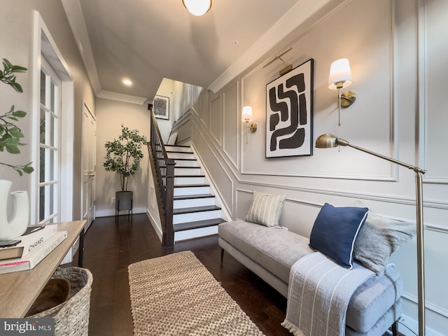 living area featuring stairway, a decorative wall, and wood finished floors