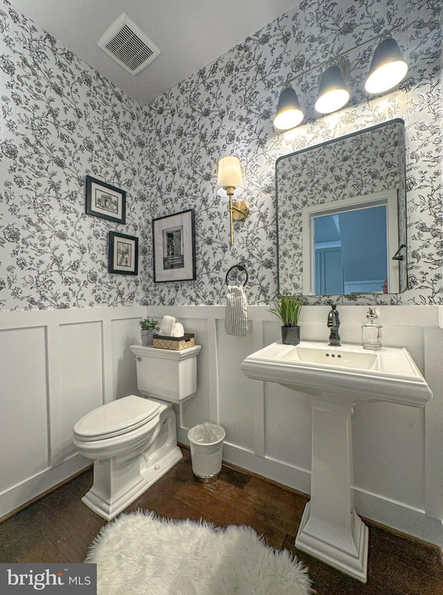 half bath featuring wainscoting, wallpapered walls, wood finished floors, and visible vents