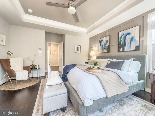 bedroom with baseboards, a raised ceiling, ceiling fan, and wood finished floors