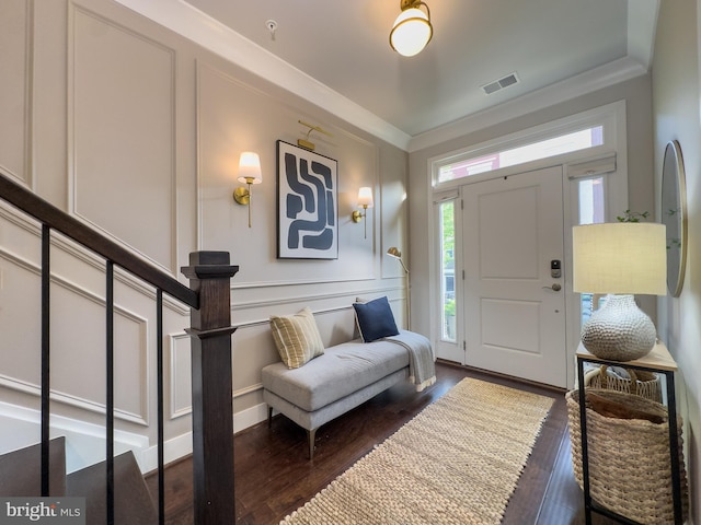 entryway with visible vents, crown molding, wood finished floors, and stairway