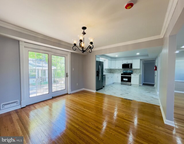 unfurnished living room featuring light wood-style floors, crown molding, and an inviting chandelier