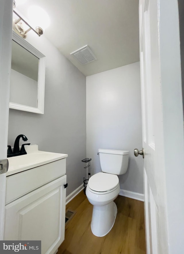 bathroom with toilet, baseboards, visible vents, and wood finished floors