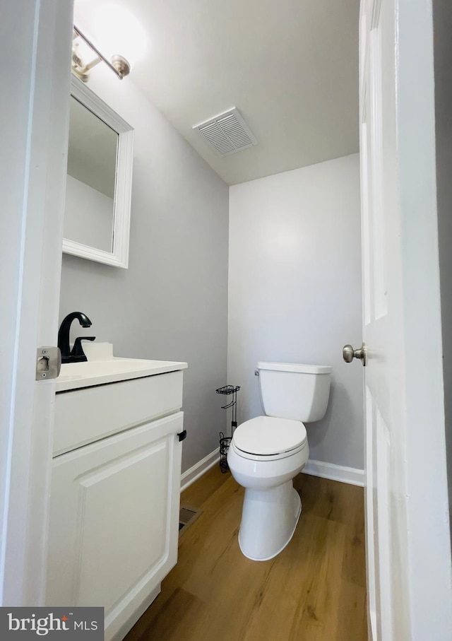 bathroom featuring toilet, baseboards, visible vents, and wood finished floors