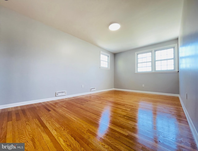spare room with baseboards, light wood finished floors, and visible vents