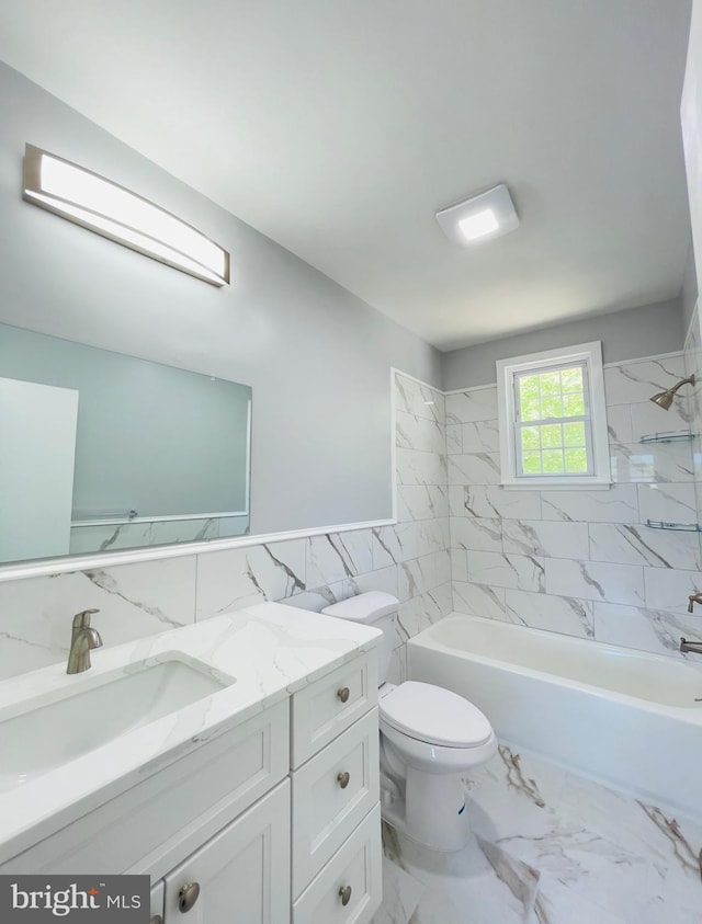 bathroom featuring vanity, toilet, tile walls, a wainscoted wall, and shower / bath combination
