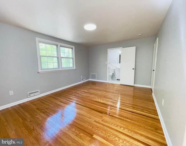 empty room with baseboards, visible vents, and wood finished floors