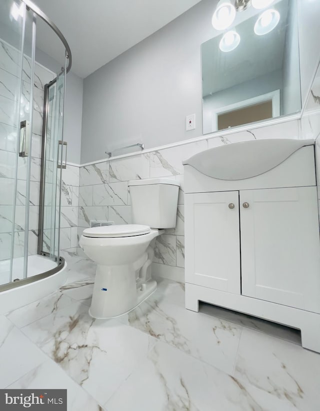 full bathroom featuring wainscoting, vanity, toilet, a marble finish shower, and tile walls