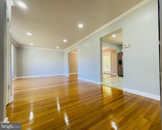 spare room featuring crown molding, recessed lighting, baseboards, and light wood-style floors