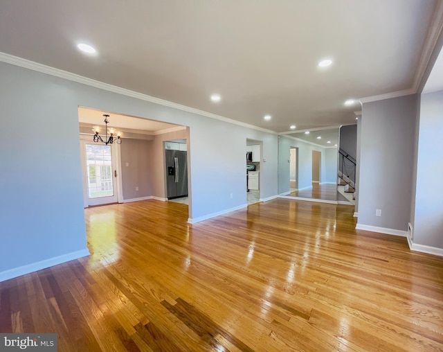 unfurnished living room featuring crown molding, light wood-style floors, stairs, and a notable chandelier