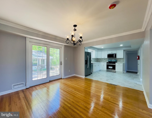 unfurnished living room featuring visible vents, light wood-style flooring, baseboards, and an inviting chandelier
