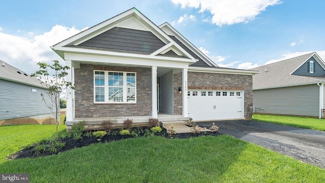 craftsman-style home with a porch, driveway, a garage, a front lawn, and stone siding