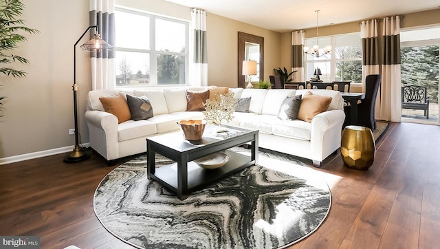 living area with baseboards, a notable chandelier, and dark wood finished floors