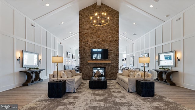 living area featuring a healthy amount of sunlight, high vaulted ceiling, a fireplace, and wood finished floors