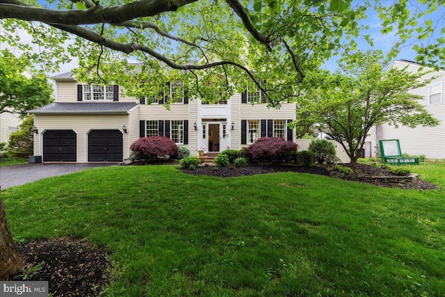 view of front of house featuring driveway, a front lawn, and an attached garage