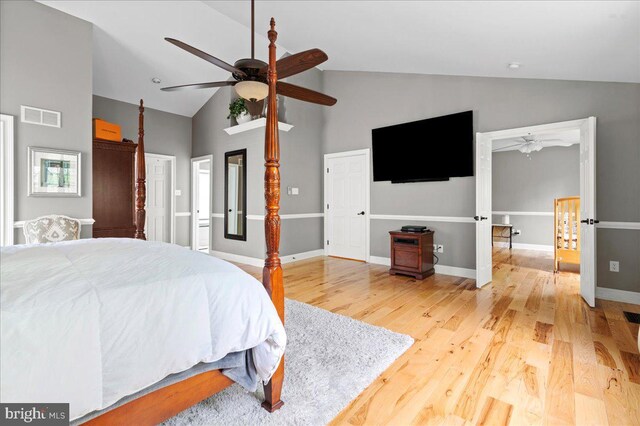 bedroom with light wood-type flooring, high vaulted ceiling, baseboards, and a ceiling fan