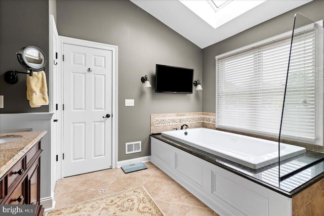 full bath featuring lofted ceiling, a skylight, a garden tub, tile patterned floors, and vanity