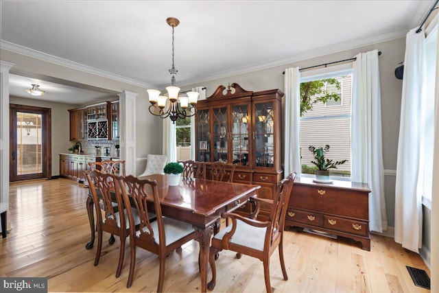 dining space featuring a chandelier, light wood-style flooring, plenty of natural light, and crown molding