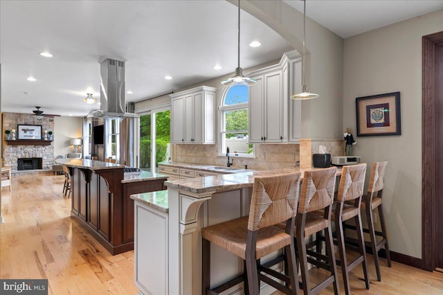 kitchen with a sink, island exhaust hood, ceiling fan, light wood-type flooring, and recessed lighting